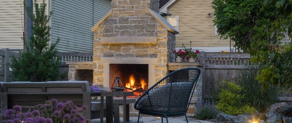Outdoor fireplace in Wauwatosa, WI, burning wood and a chair.