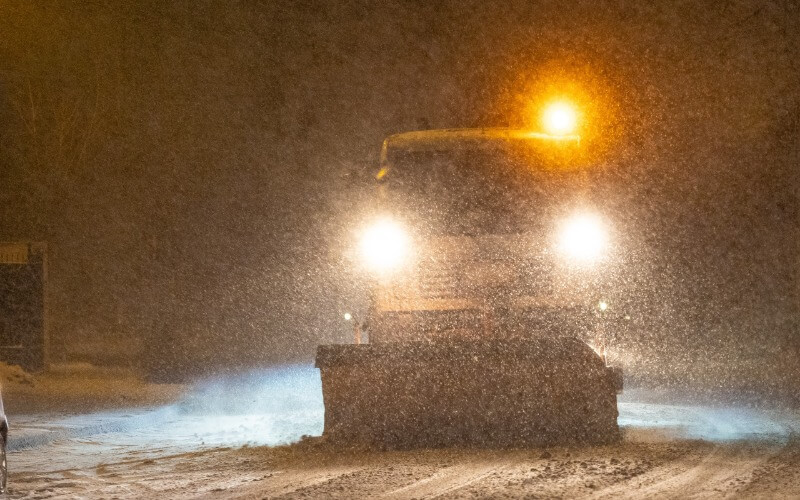 Snow plow clearing parking lot at night