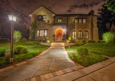 Large house with pavers leading to front door at nighttime